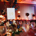 Wine glasses on the served table with lightening candles and table number on it